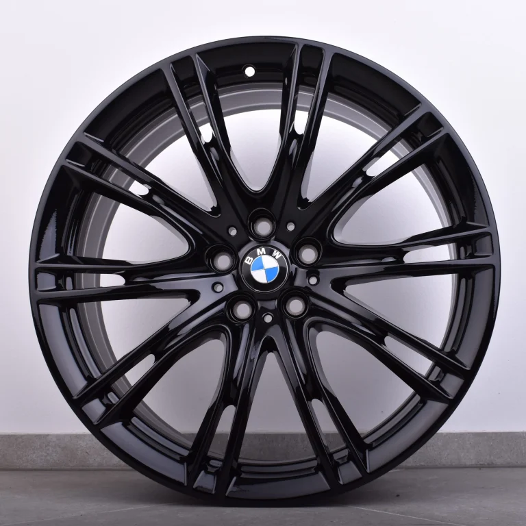 Glanzschwarz lackierte BMW Felge mit Mehrspeichen-Design vor weißer Wand